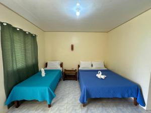 董索Dancalan Beach Resort的配有蓝色床单的客房内的两张床