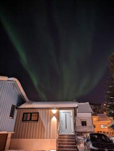 特罗姆瑟Northern living 1 room with shared bathroom的天空中点亮北灯的房子