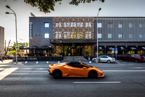 科马尔诺HOTEL EUROPA的一辆橙色汽车在建筑物前的街道上行驶