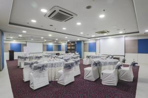 新德里Hotel Bluestone - Nehru Place的宴会厅配有白色的桌椅和屏幕