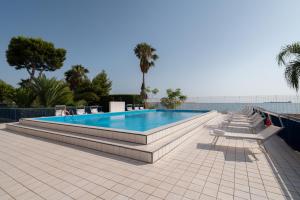 塔兰托Hotel Delfino Taranto的一座游泳池,在庭院内围着长椅