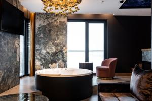 克拉科夫Art Suites Luxury Hotel的带浴缸和椅子的大浴室