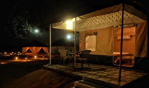 RājgarhBundeli Resorts的帐篷,晚上配有两把椅子和一张桌子
