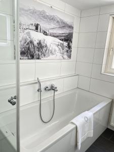 布雷根茨Stylische Wohnung im Herzen von Bregenz mit privatem Parkplatz的配有白色浴缸的带绘画的浴室