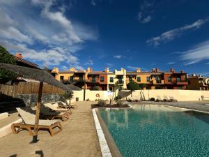 圣米格尔德阿沃纳San Blas Golf del Sur Residence的一座带椅子和遮阳伞的游泳池位于一座建筑旁边