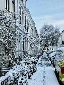 不莱梅Zentrales und ruhiges Apartment im beliebtesten Bremer Viertel的一条雪覆盖的街道上,汽车停在大楼旁边