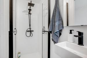 哥本哈根Perfectly located cozy apartment的带淋浴和盥洗盆的白色浴室