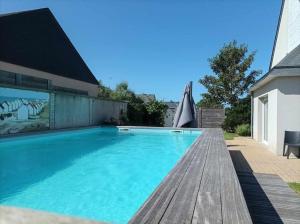 阿贡库坦维尔Grande maison de vacances的一座带木甲板的游泳池,位于一座房子旁边