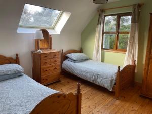 莱特弗拉克Letterfrack Mountain Farm Cottage on farm in village centre的一间卧室设有两张单人床和一个窗户。