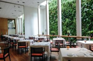 圣保罗埃米利亚诺酒店的一间设有白色桌椅的餐厅,种植了植物