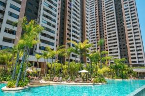 圣保罗Piscine Resort Brás的一座棕榈树环绕的游泳池,位于高楼前