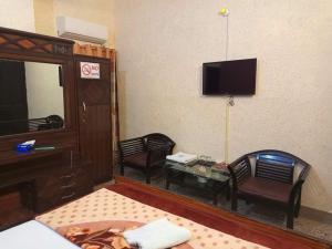 卡拉奇Furnish Rooms Near Jinnah Airport的配有电视、两把椅子和一张桌子的房间