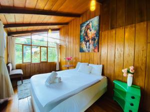 明多Wooden House Mindo - Casa de Las Nevadas的卧室配有一张白色大床,位于木墙内