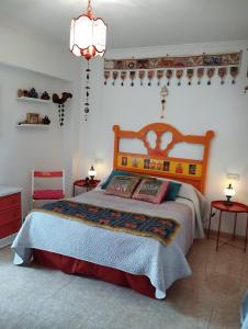 马拉加La Casa de La Abuela Rosy的一间卧室配有一张床、两张桌子和一个吊灯。