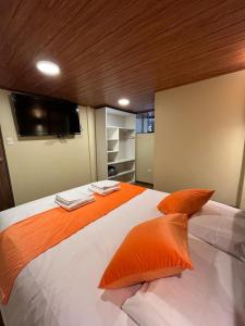 库斯科Casa Virgen del Carmen的卧室内的一张带橙色枕头的大床