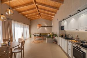 凯法利尼亚岛Apeiron Villas的一间厨房和一间带木制天花板及桌子的客厅