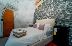 巴拉奥纳省圣克鲁斯Ovalulú Glamping Hotel的卧室配有白色的床铺和石墙