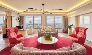 马德里马德里欧式建筑NH精选酒店的客厅配有红色椅子,还有人坐在书桌旁