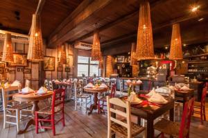 格拉玛多Duplex Cobertura - Gramado Wish Serrano的餐厅设有桌椅和吊灯。