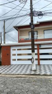 索莱马Casa nova condomínio fechado Praia Grande SP的房屋前的柱子,有白色车库门