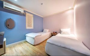 首尔Sinchon Gaon Hostel的蓝色墙壁客房的两张床