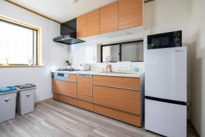 东京匯家風花ビル的厨房配有木制橱柜和白色冰箱。