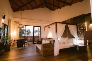 爱妮岛Nacpan Beach Resort的一间带一张天蓬床的卧室,位于带桌子的房间内