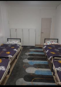 阿拉木图ДОМ Hostel的带三张床的客房,铺有地毯