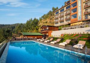KīarjüSTa Cliffend Resort & Spa, Mashobra的一个带躺椅的游泳池和一间酒店