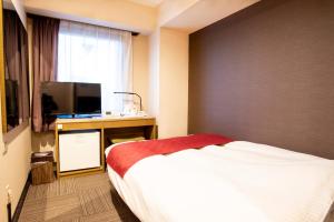 草津町le Lac HOTEL KUSATSU的一间卧室配有一张床和一张书桌及电视