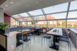 布兰肯贝赫考森当克沙丘圩田酒店的餐厅设有桌椅和大窗户。