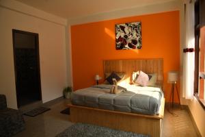 卡索尔Himtrek Stays, Kasol的一间卧室配有一张橙色墙壁的床