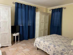 马达莱纳德帕可别墅酒店的一间卧室配有蓝色窗帘、一张床和电视