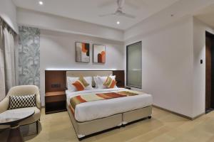 苏拉特Hotel Elements Surat的一间卧室配有一张特大号床和一把椅子