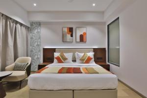苏拉特Hotel Elements Surat的一间卧室配有一张大床和一把椅子