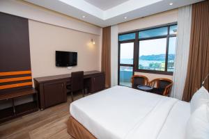 姆万扎金冠酒店的酒店客房配有一张床、一张书桌和一台电视。