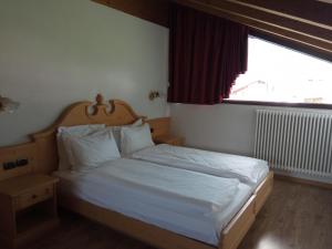 费拉迪普利米罗Hotel Castel Pietra的一间卧室配有一张带白色床单的床和一扇窗户。