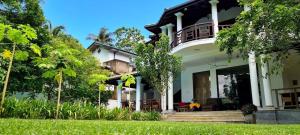 乌纳瓦图纳Star Light Villa的一座带门廊和树木的大型白色房屋
