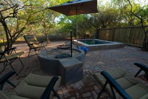 侯斯普瑞特Bushveld Jewel - Close to Kruger的庭院设有火坑、椅子和遮阳伞