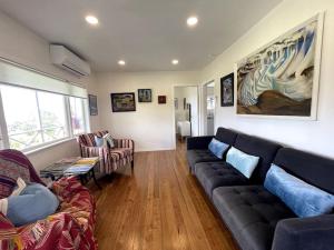 Matauri BayMatauri Bay Shearer's Cottage的客厅配有黑色真皮沙发和椅子