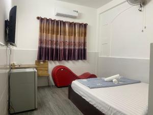 胡志明市Thanh Hương Hotel的小房间设有一张床和一把红色椅子