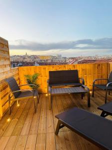 马赛Honoré - Rooftop- Centre Vieux Port的阳台上的木制甲板上配有桌椅