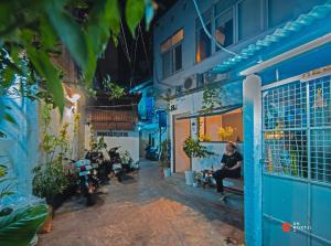 胡志明市8h-hostel的坐在蓝色建筑前面的长凳上的女人