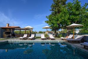普拉坦斯Platanias Villa Spyros的游泳池旁设有躺椅和遮阳伞