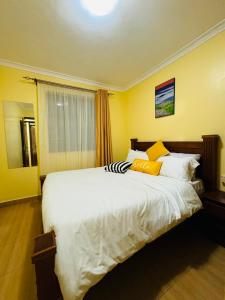Langata RongaiLovely 2 Bedroom Apartment in Ongata Rongai的卧室设有一张白色大床和黄色的墙壁