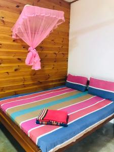 亭可马里Walkers hostel的配有一张带粉红色伞的床的房间