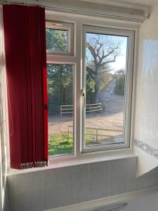 新港Heath Farm cottage的浴室的窗户,有红色窗帘