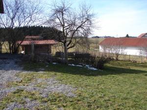 ArgenbühlBlockhaus im Permakulturgarten的田野里的房子,有树和栅栏