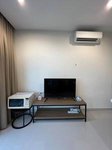 古晋Kozi Square Dual Unit (1 bedroom, 1 living room)的客厅配有电视和带微波炉的桌子。