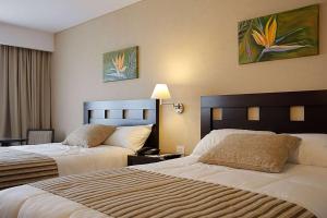 富内斯Howard Johnson Hotel & Resort Funes的酒店客房设有两张床和一张桌子。